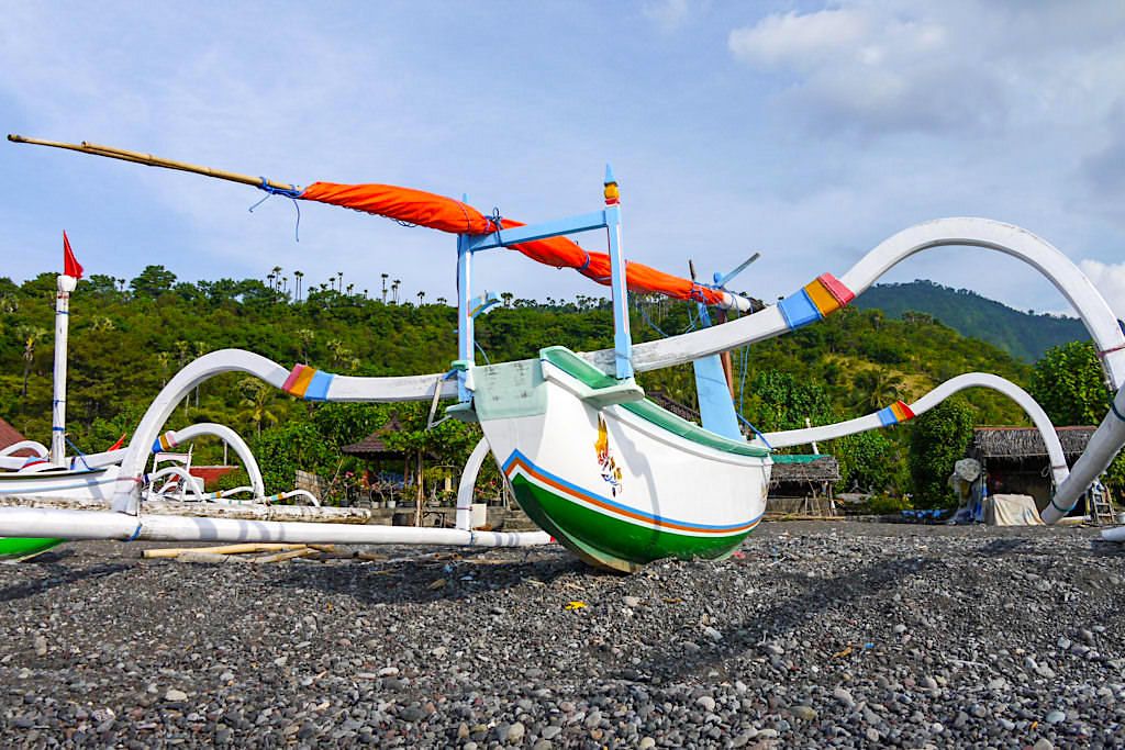 Dunkler Kiesstrand und typische Fischerboote bei Amed Bali - Indonesien